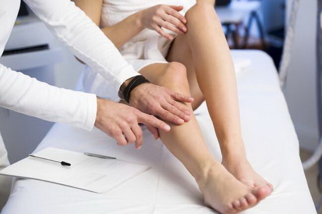 The doctor examines the foot with reticular varicose veins